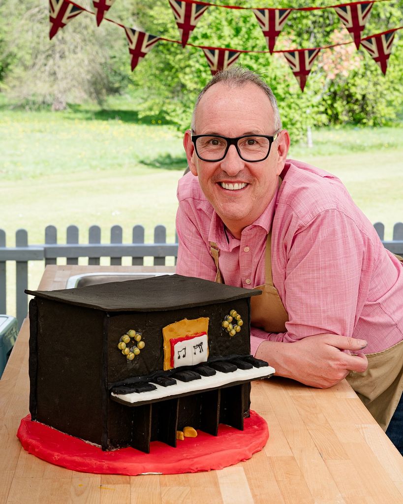 A man stands next to a gingerbread house