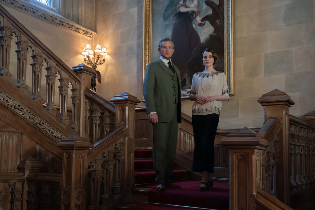 Hugh Bonneville and Michelle Dockery stand on stair case for photograph