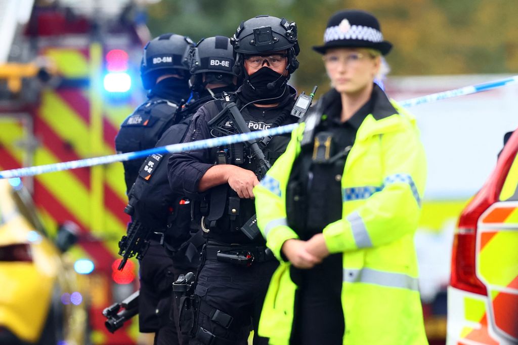 Armed police officers stand with their weapons 