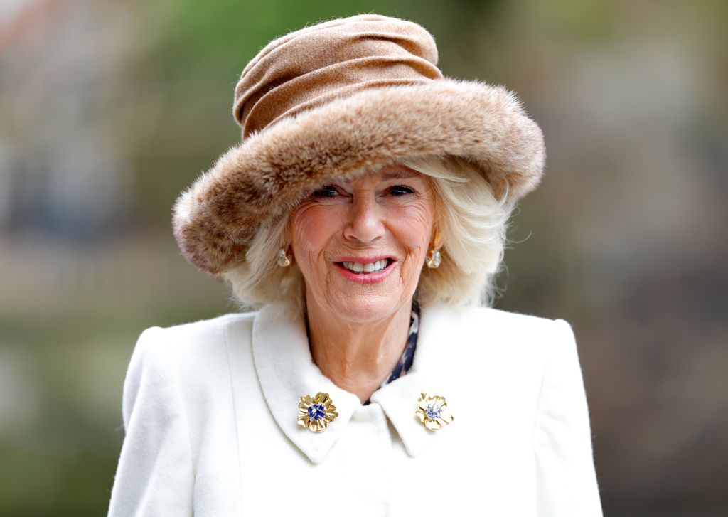 Queen Camilla smiling and wearing a furry hat 