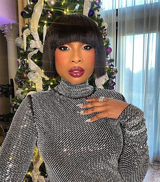 Jennifer Hudson in a silver dress in front of a Christmas tree
