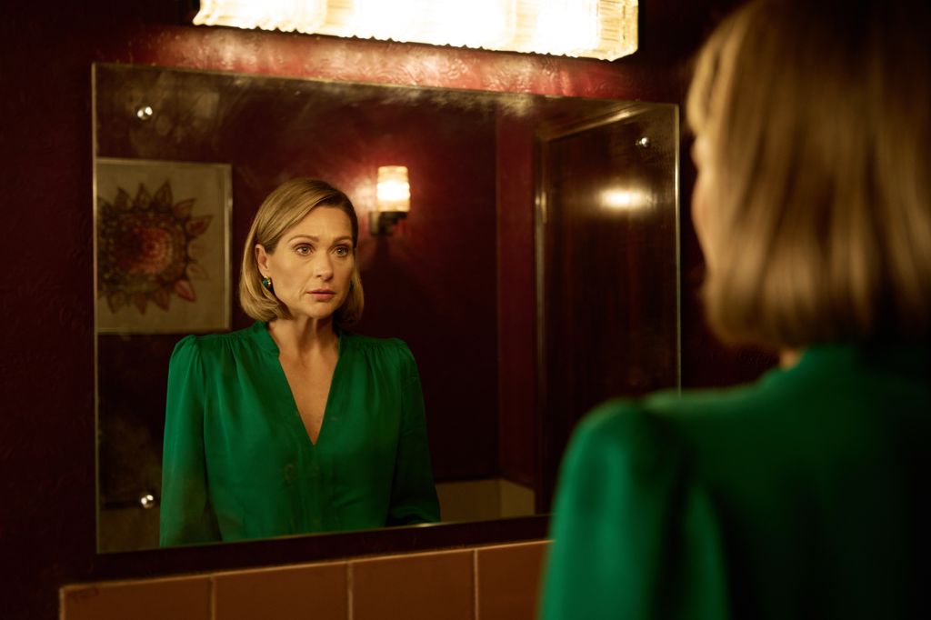 Blonde woman looking into a mirror wearing green dress