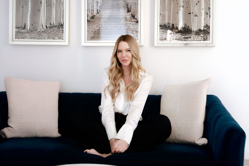 Young blonde woman in a white shirt sitting on a plush blue sofa