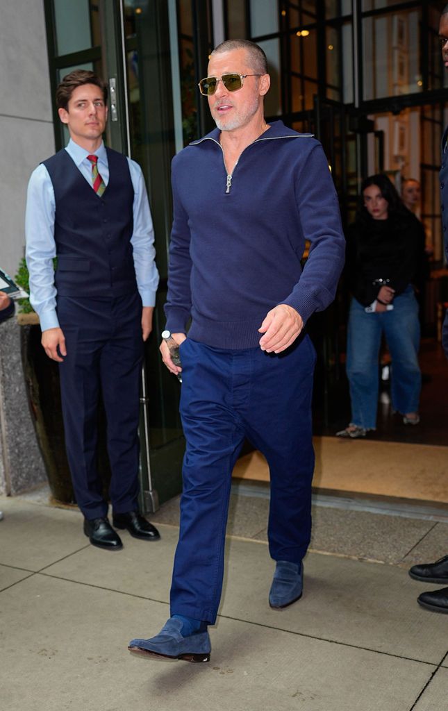 Brad Pitt wears a navy quarter zip knit top with matching trousers and loafers as he leaves a hotel in New York