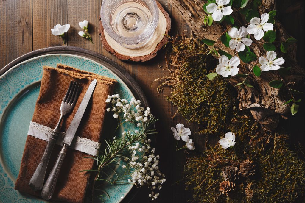 Plate and cutlery with moss, flower and old piece of wood