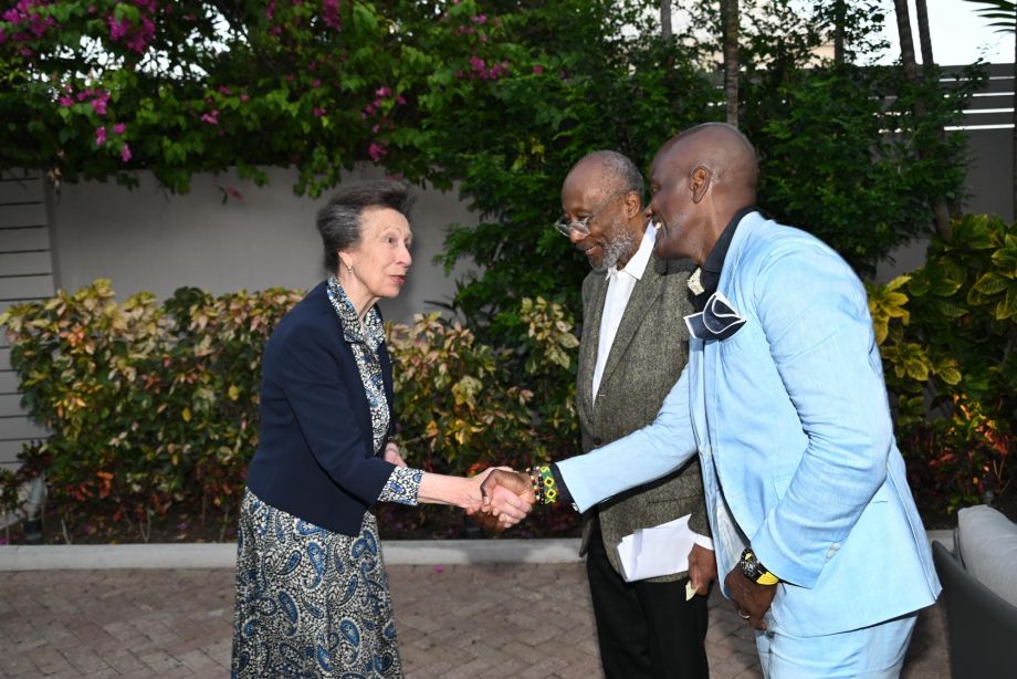 Princess Anne shaking hands with a man in a blue suit while on a visit to Barbados