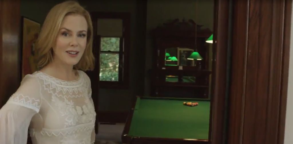 Nicole Kidman in a white dress in the doorway of a games room