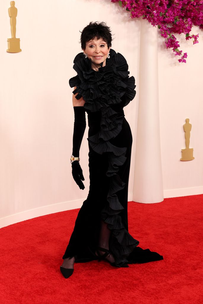 Rita Moreno posant et souriant dans une longue robe à volants noires