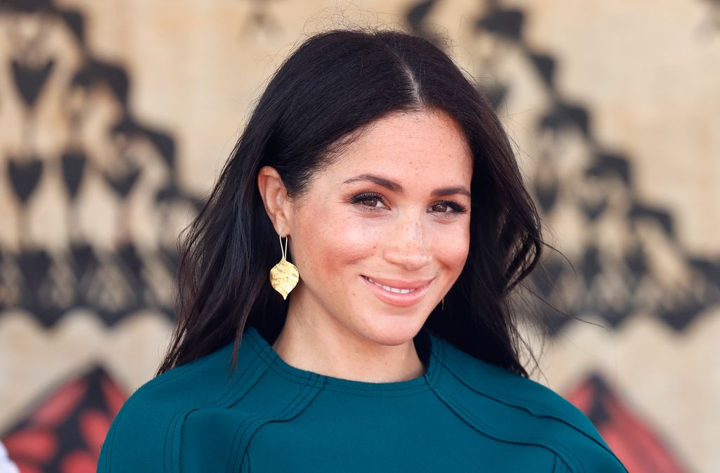 Meghan, Duchess of Sussex smises in teal dress