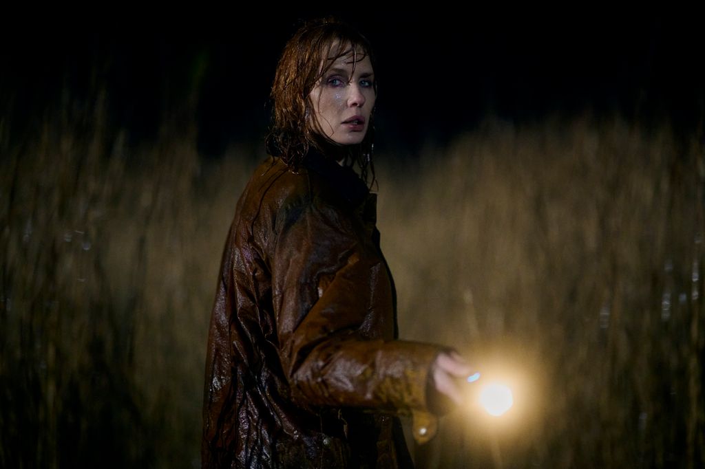 woman holding torch in field at night