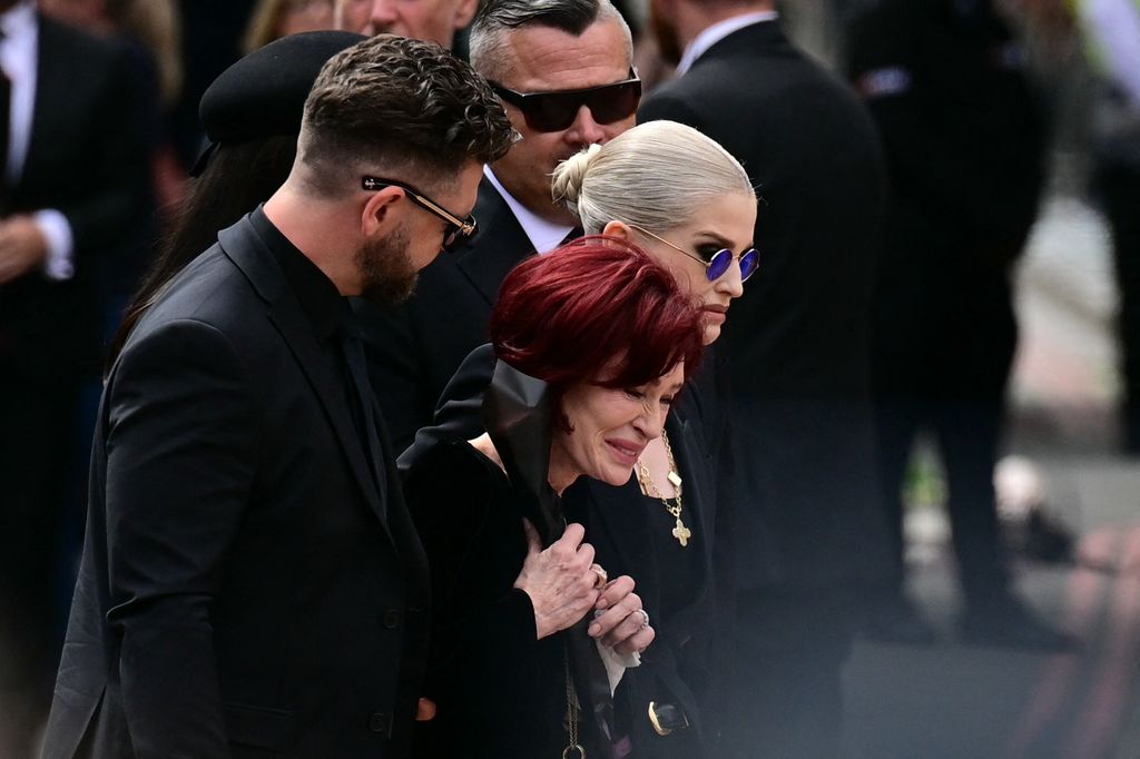 TOPSHOT - The family of Ozzy Osbourne, son Jack Osbourne (L), window Sharon Osbourne (C) and daughter Kelly Osbourne (R) arrive to lay flowers at the Black Sabbath Bridge bench on Broad Street during a funeral procession for Ozzy Osbourne, the late lead singer of Black Sabbath, in Birmingham, central England on July 30, 2025. Thousands are expected to line the streets in Ozzy Osbourne's UK hometown of Birmingham on Wednesday to honour the heavy metal hell-raiser Ozzy Osbourne as he is laid to rest. Osbourne, nicknamed the "Prince of Darkness" and who once bit a bat while on stage while performing with his Black Sabbath band, died on July 22 at the age of 76. (Photo by Ben STANSALL / AFP) (Photo by BEN STANSALL/AFP via Getty Images)          
