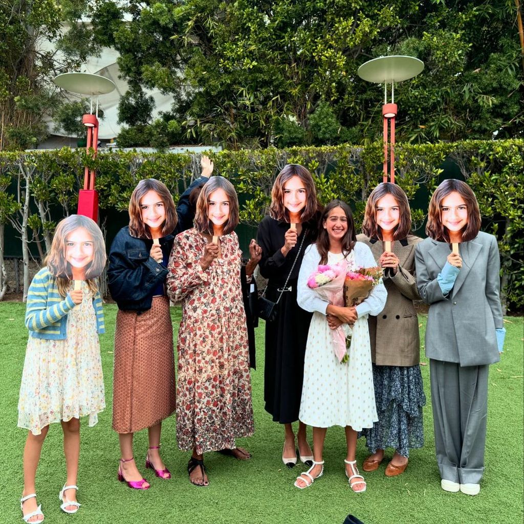 Emma Heming's daughter Mabel (third right) stands with her blended family who cover their faces with masks of Mabel's face