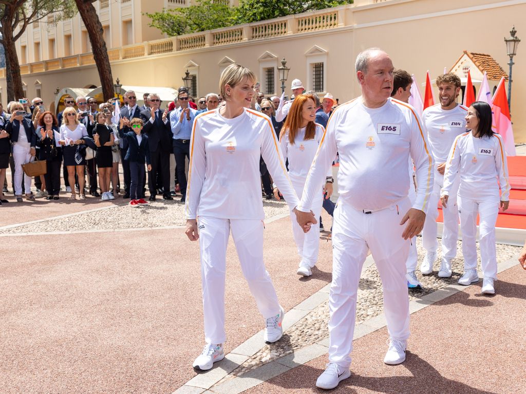 Princess Charlene and Prince Albert walking in white Olympic gear