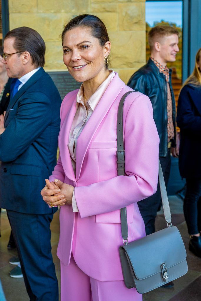 Victoria in pink suit with blue bag