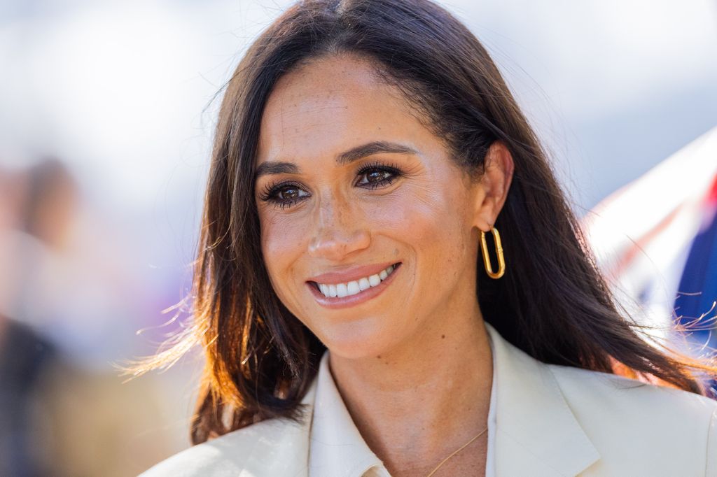 The Duchess of Sussex smiling with gold hoop earrings