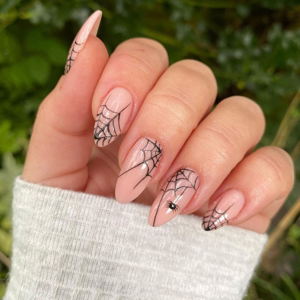 This design features intricate spider webs on a soft, nude base, with a tiny spider making a surprise appearance. It’s a hauntingly beautiful way to add some spooky sophistication to your nails.