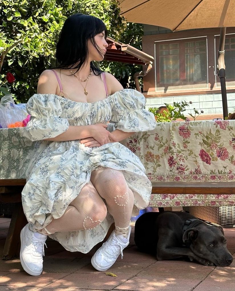 Billie EIlish wears a floral off-the-shoulder-dress and sits in her family's garden on Easter