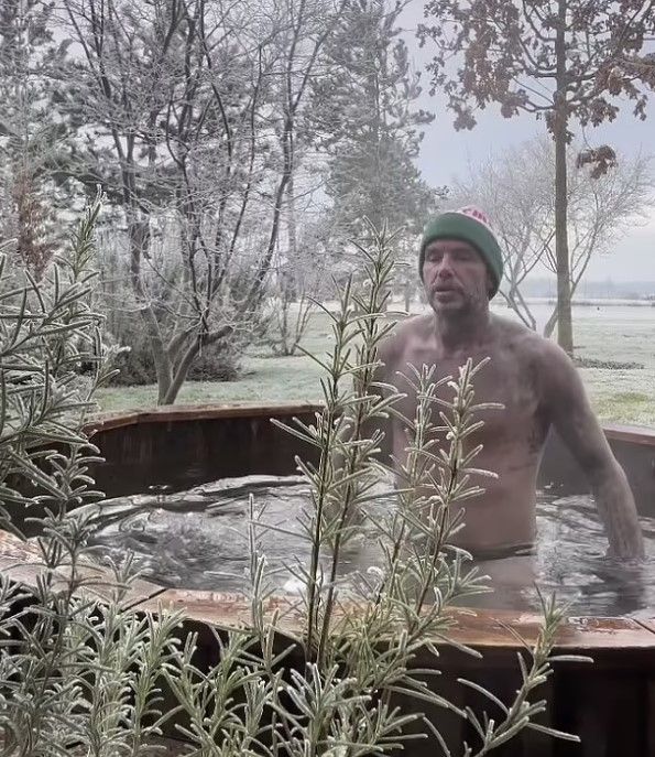 Shirtless David Beckham in underpants and hat submerging self in ice bath