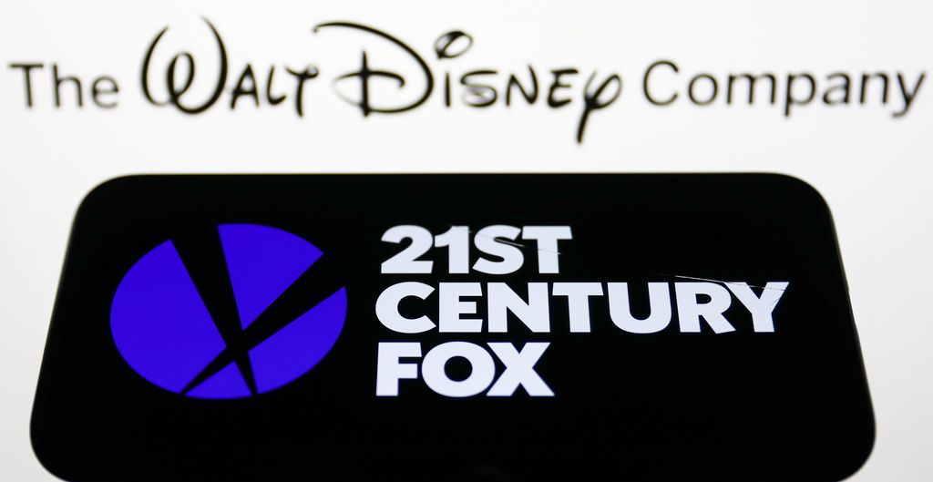 21st Century Fox logo displayed on a phone screen and The Walt Disney Company logo displayed on a screen are seen in this illustration photo taken in Krakow, Poland on August 20, 2022