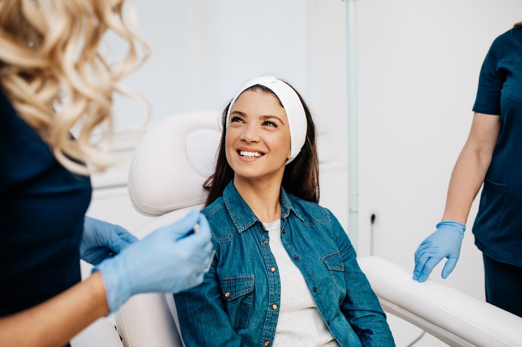 Attractive pretty woman consults with a beautician about anti-aging treatments and rejuvenating facial injections at beauty clinic.  Self care concept.