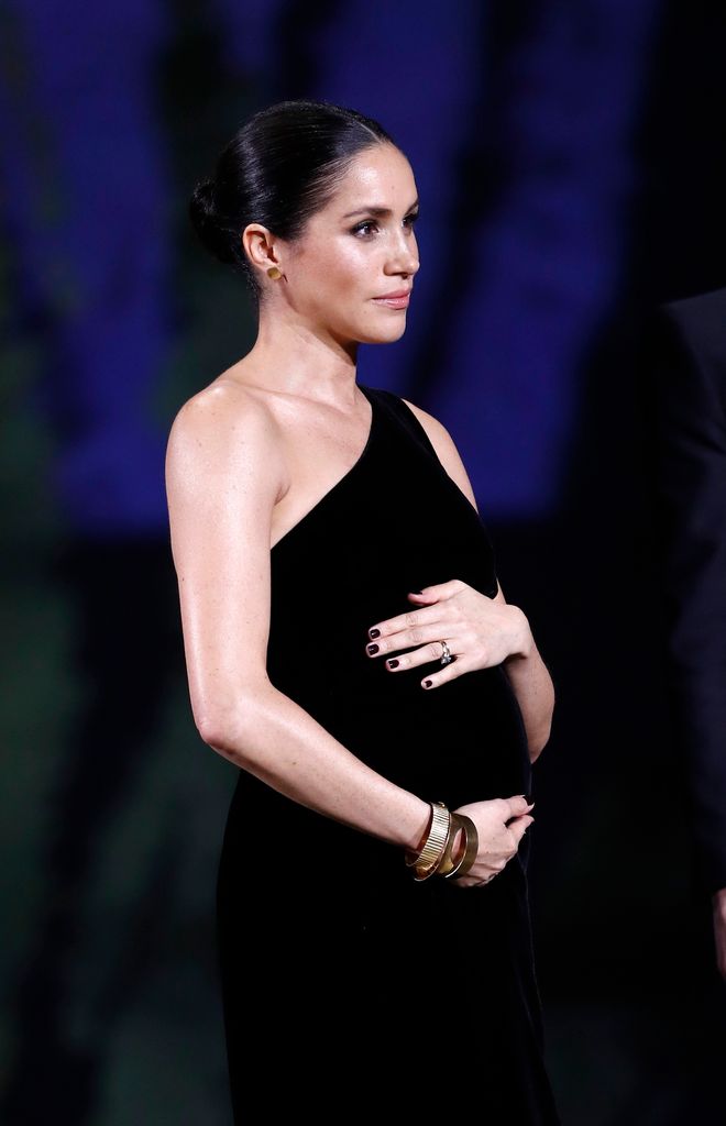 Meghan, Duchess of Sussex cradling bump in black dress
