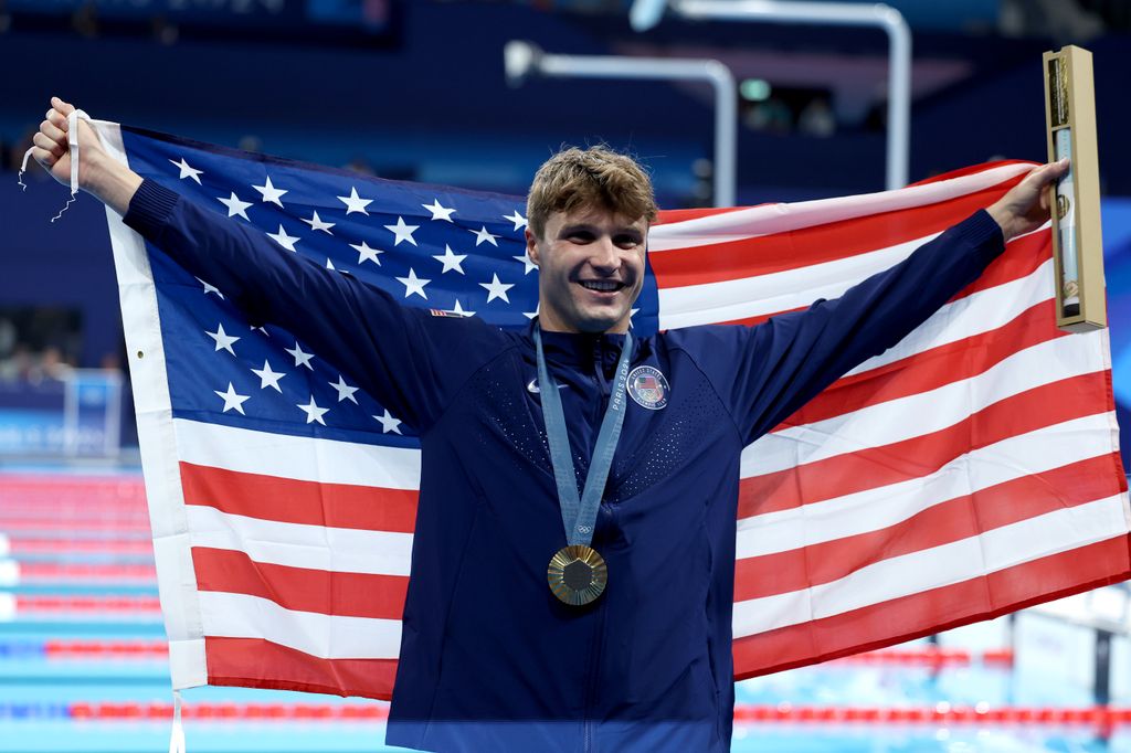 Gold Medalist Bobby Finke of Team United States poses with the national flag of the United States following the Swimming medal ceremony after the Men's 1500m Freestyle Final on day nine of the Olympic Games Paris 2024 at Paris La Defense Arena on August 04, 2024 in Nanterre, France.