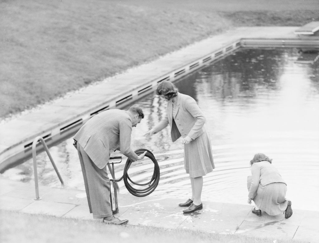King George VI, Princess Elizabeth and Princess Margaret collect water from a swimming pool at the Royal Lodge