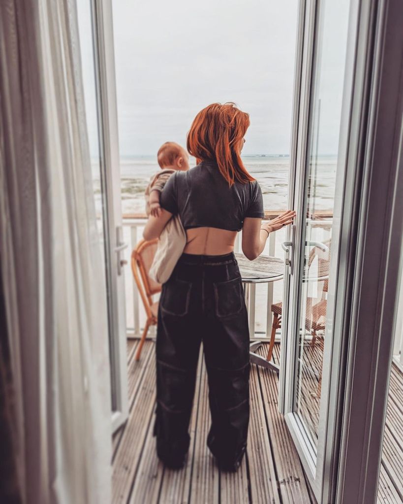 stacey dooley holding daughter minnie on terrace overlooking sea