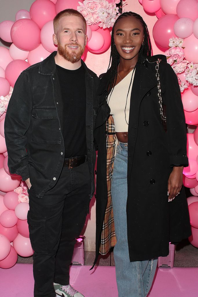 Chyna Mills and Neil Jones smiling together in front of a balloon wall