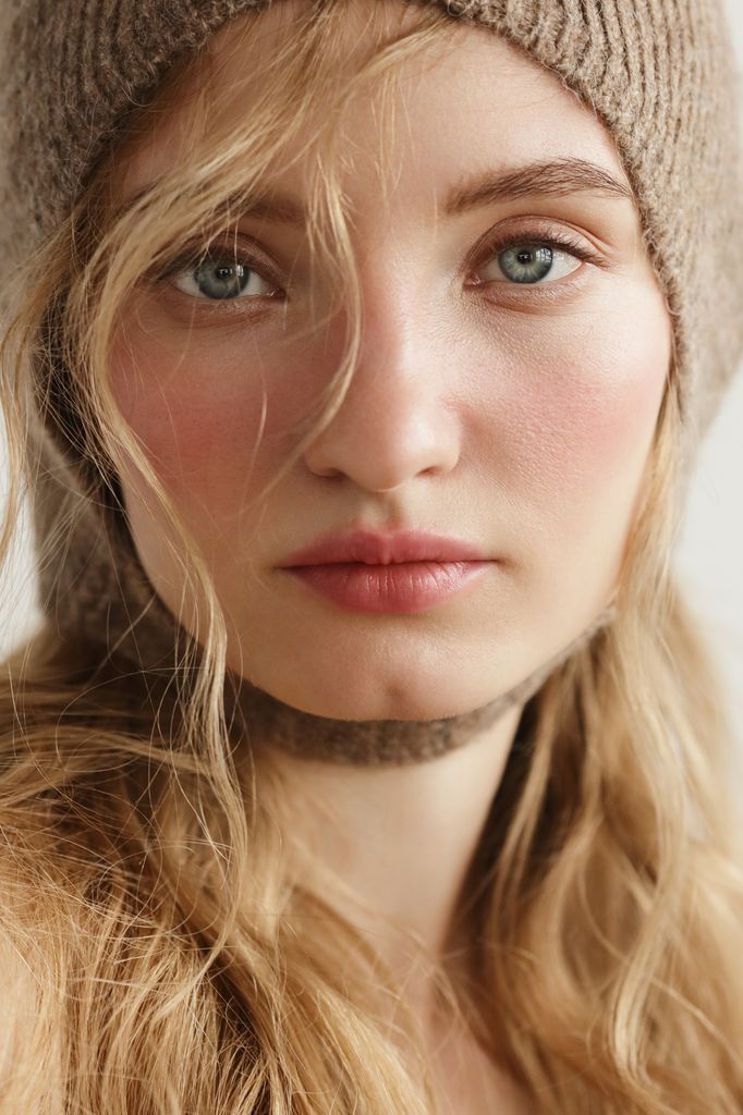 Portrait of young beautiful woman wearing beige knitted hood
