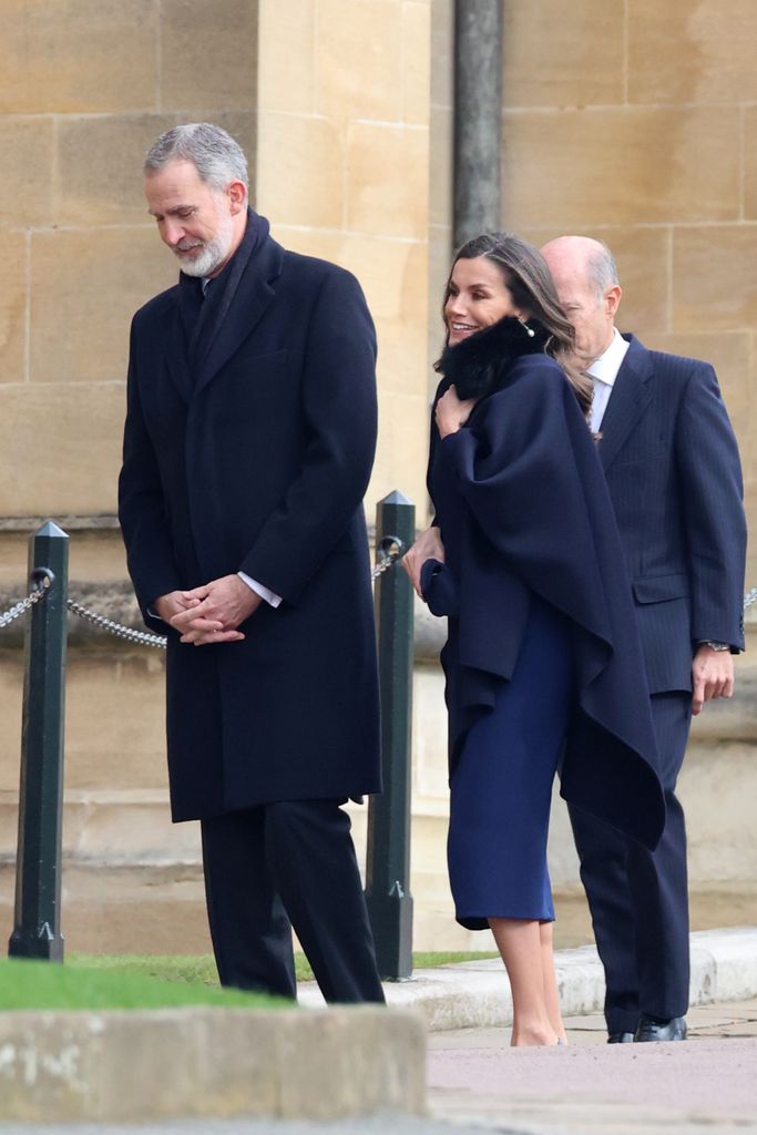 Queen Letizia holding her scarf as she walked with her husband King Felipe