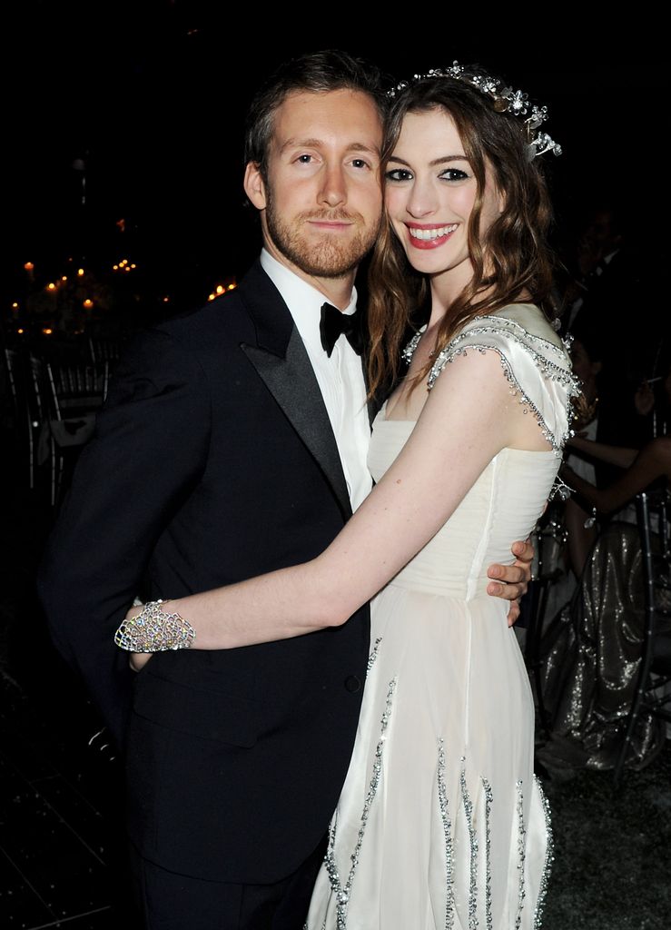 Anne Hathaway in a white sparkly dress with arms around Adam Shulman in a suit