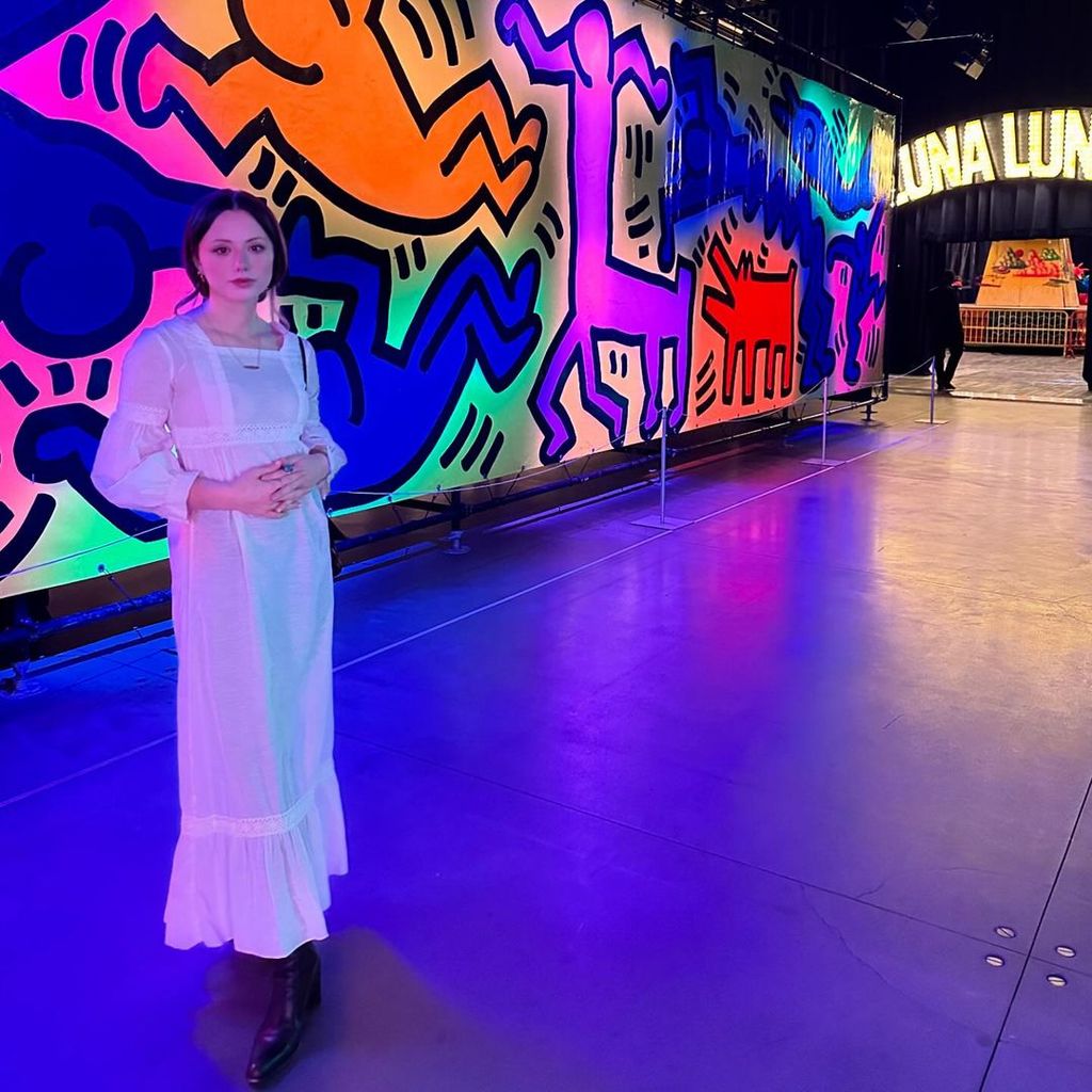 Lily Sheen stands in front of neon wall at NYC amusement park