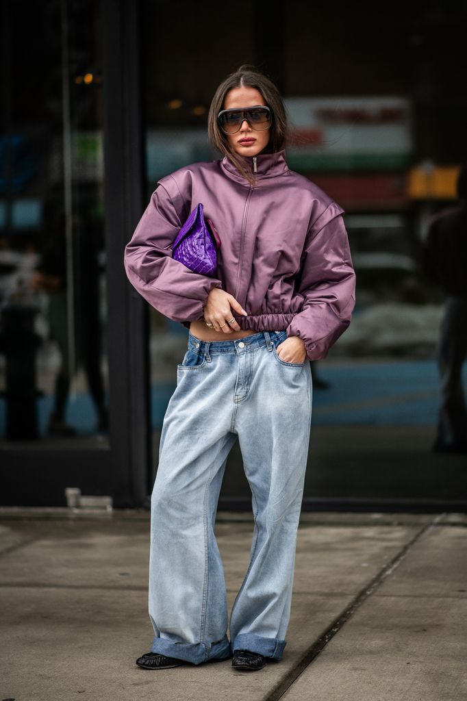 Un invité de la NYFW pose dans une veste violette et un jean dans la rue