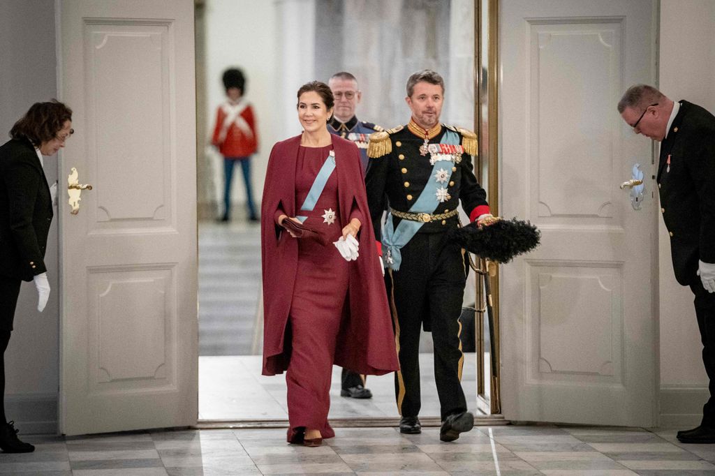 Mary in a burgundy caped gown with frederik in castle