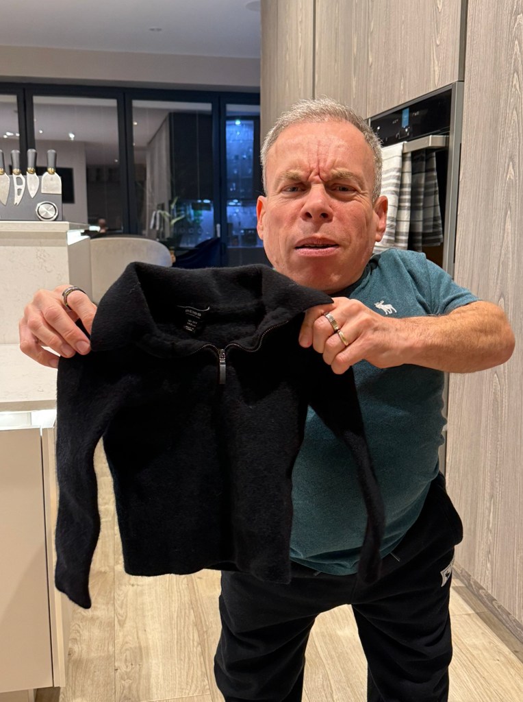 Warwick Davis tenant un sauteur à la maison