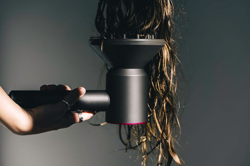  woman using hair dryer with diffuser on wavy hair
