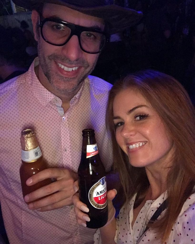 Isla Fisher holding up a beer with Sasha Baron Cohen