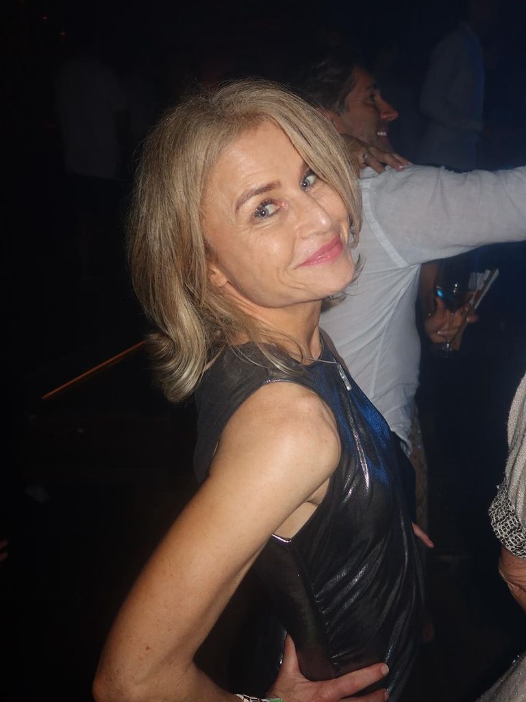 Woman in her 50s smiling over her shoulder in a club