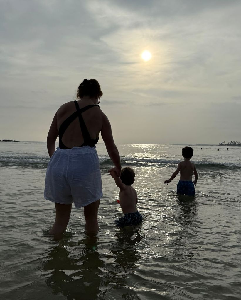 Eugenie on beach from behind with sons