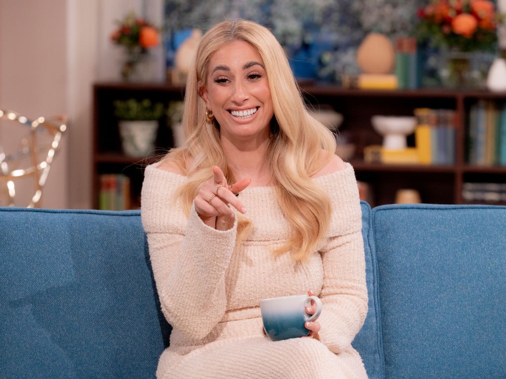 Stacey Solomon in white fluffy jumper dress holding a mug while sitting on the This Morning sofa