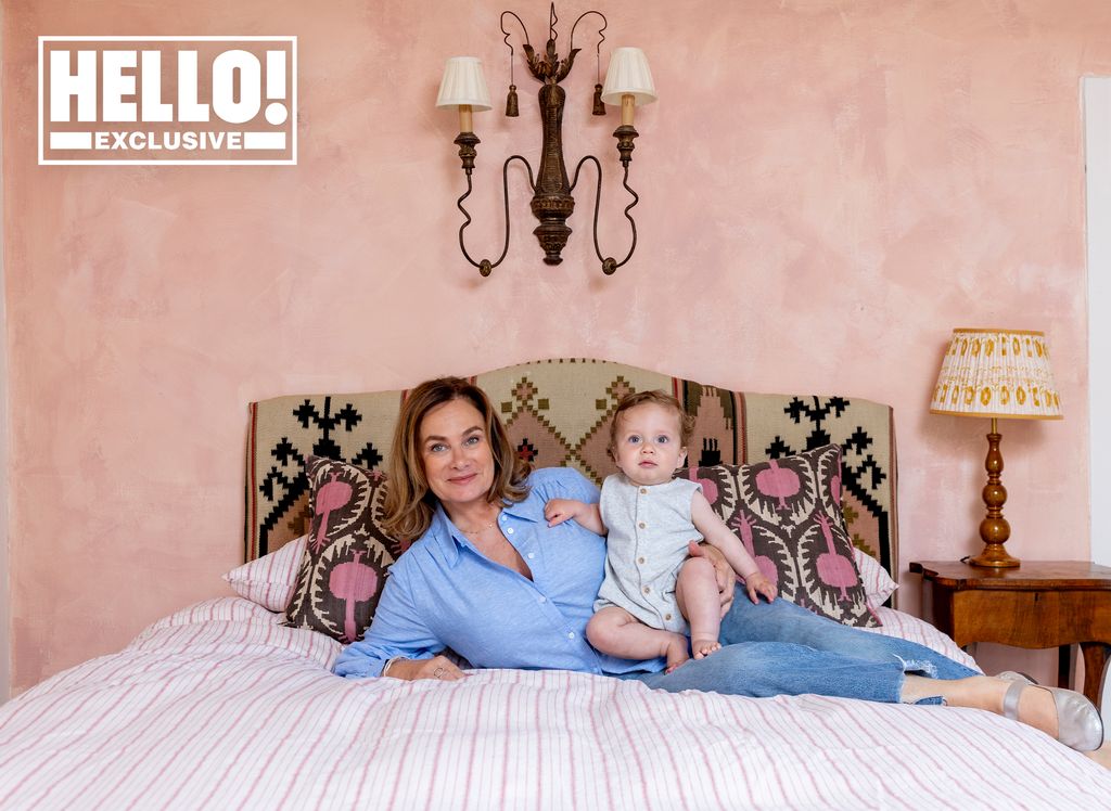 Penelope Chilvers posing on bed in pink bedroom at Cotswolds home