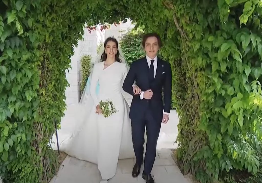 Rajwa al Said in asymmetric white wedding dress with bouquet and flowers
