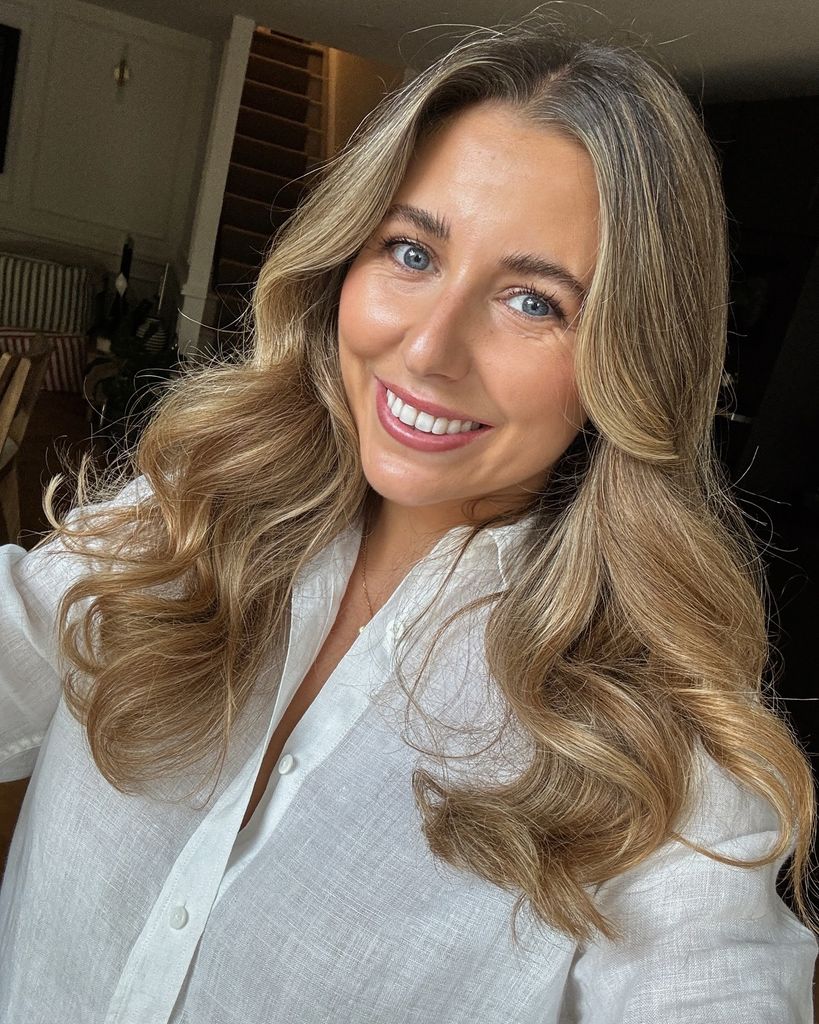 Young blonde woman smiling for a selfie in a white shirt