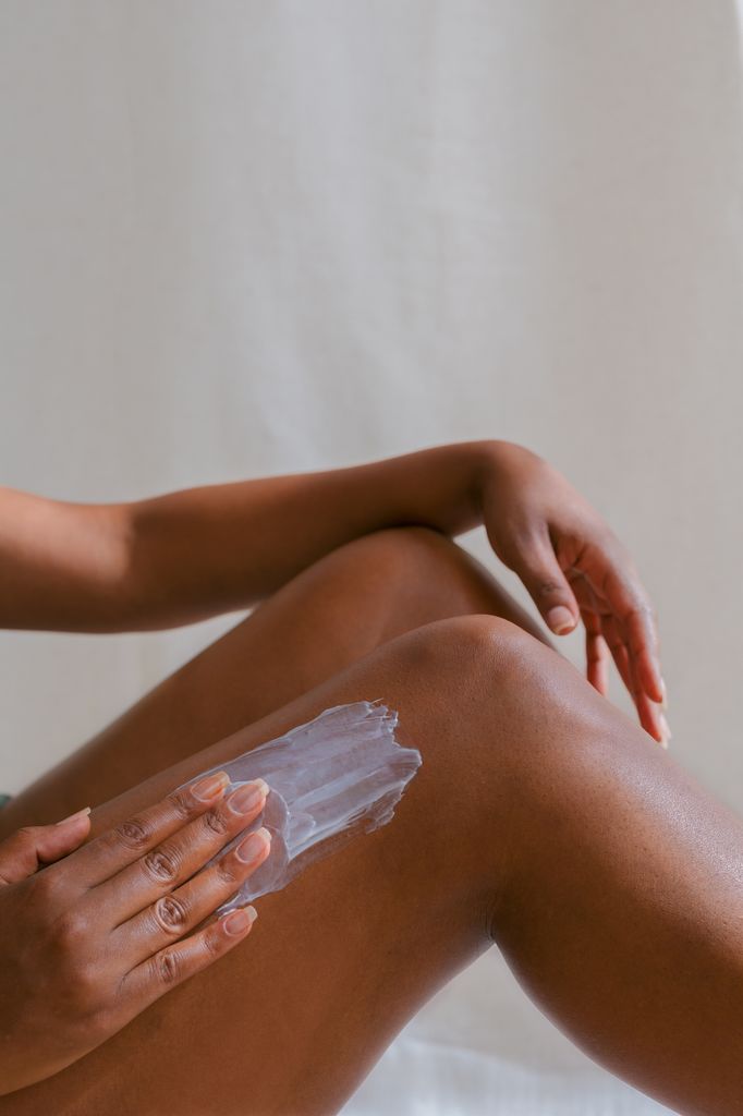 Unrecognizable woman applying lotion on her leg. Concept of beauty and personal care. Skin care concept.