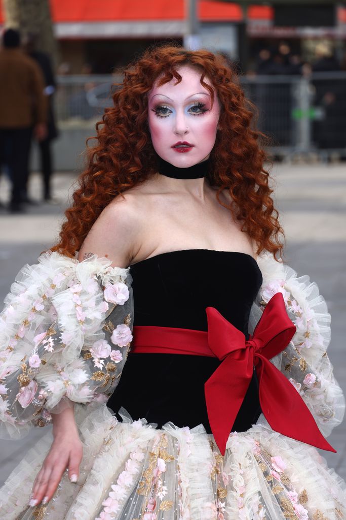 Chappell Roan standing on a road in Paris posing for photographs at PFW