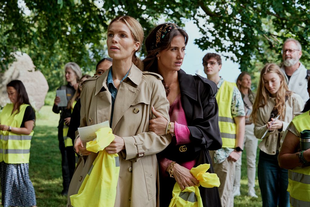 two women standing in busy field of people wearing hi-vis