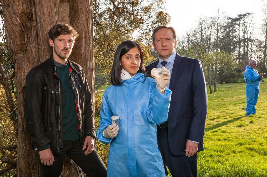 two police officers and forensic pathologist standing in field