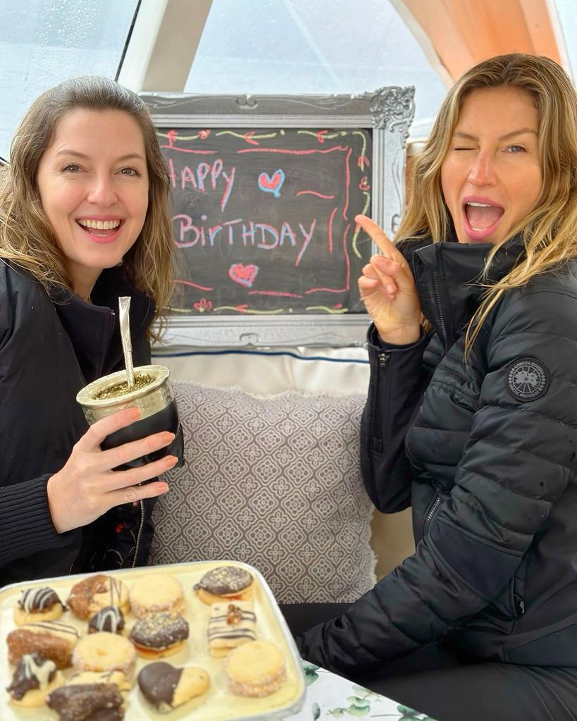 Gisele and Patricia Bündchen sitting next to a happy birthday sign