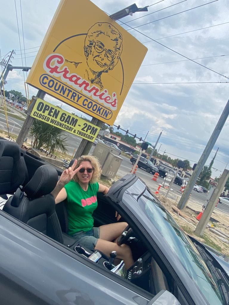 Tracey Davies giving a peace sign in an open-top car
